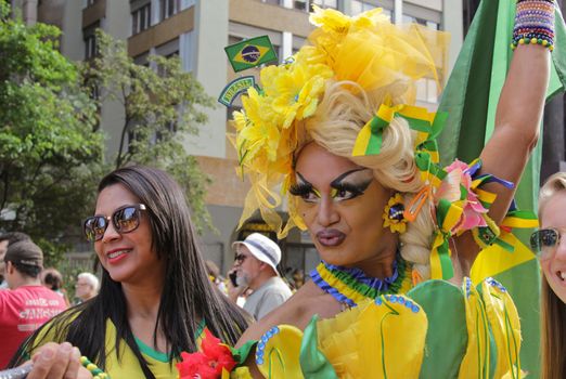 SAO PAULO, BRAZIL August 16, 2015: A drag queen called Charlene Blue with yellow and green costume poses for pictures and selfies in the protest against federal government corruption in Sao Paulo Brazil.