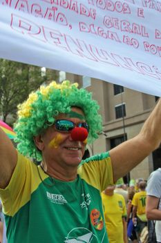 SAO PAULO, BRAZIL August 16, 2015: An unidentified man with yellow and green clown costume in the protest against federal government corruption in Sao Paulo Brazil. Protesters call for the impeachment of President Dilma Rousseff.