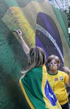 SAO PAULO, BRAZIL August 16, 2015: Two unidentified women  signing a large brazilian flag in the protest against federal government corruption in Sao Paulo Brazil.