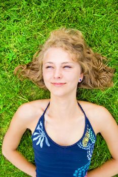 Vacation conceptual image. Young teenage girl lying on grass and relaxes.