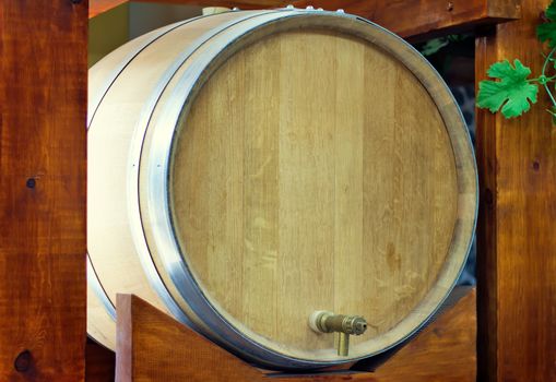 Large durable , made of natural oak, barrel for wine with a metal crane, is located on a convenient wooden stand.