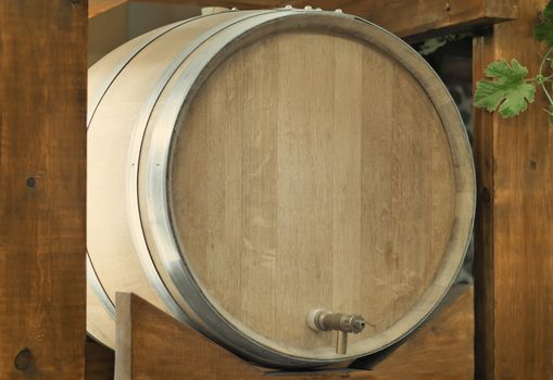 Large durable , made of natural oak, barrel for wine with a metal crane, is located on a convenient wooden stand.