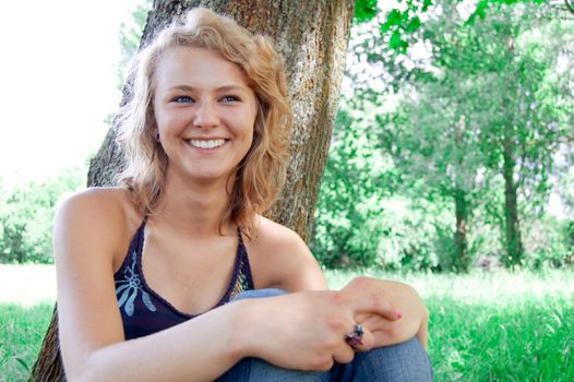 Portrait of young beautiful girl based on the park tree.