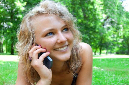 Communication conceptual image. Young beautiful girl talking on a cell phone and smiles.