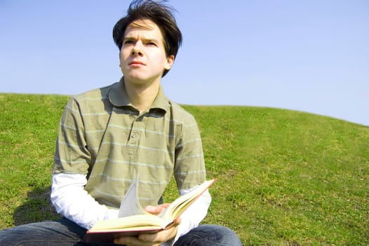Education conceptual image. Teeneger student reading a book outdoors.