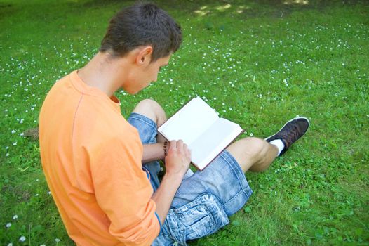 Education conceptual image. Teenager reading a book outdoors.
