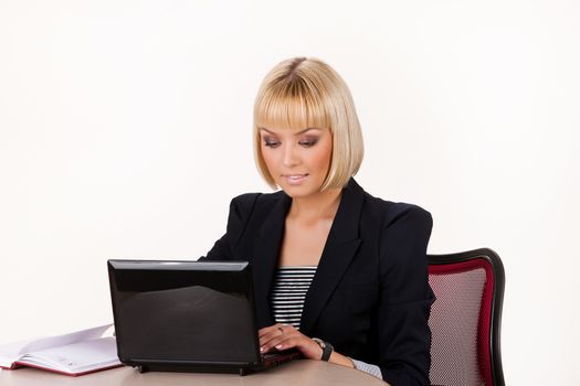 Young blonde woman working at the notebook on isolated background