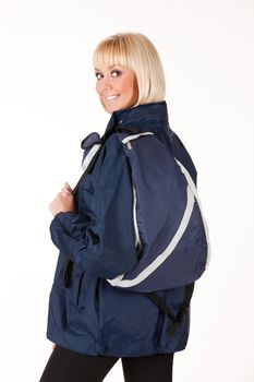 Young blonde woman in a jacket with rucksack on isolated studio background