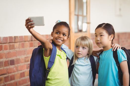 Cute pupils taking selfies at corridor in school