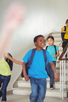 Happy pupils walking down the stairs in school