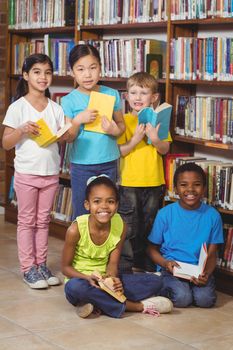 Portrait of smiling pupils with books in the library in school