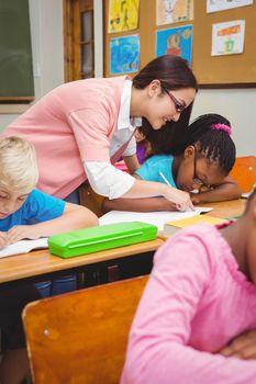 Smiling teacher helping a student at the elementary school