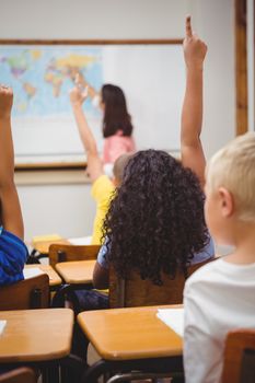 Students raising hands to answer a question at the elementary school