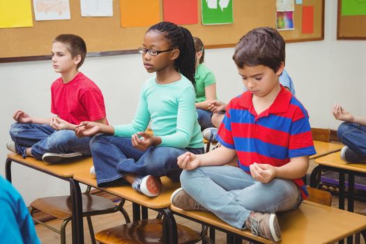 Pupils meditating on classroom desks at the elementary school