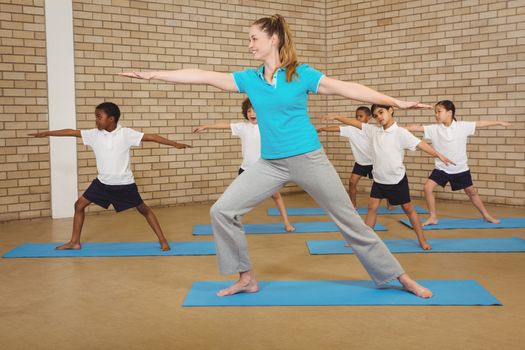 Students and teacher doing yoga pose at elementary school