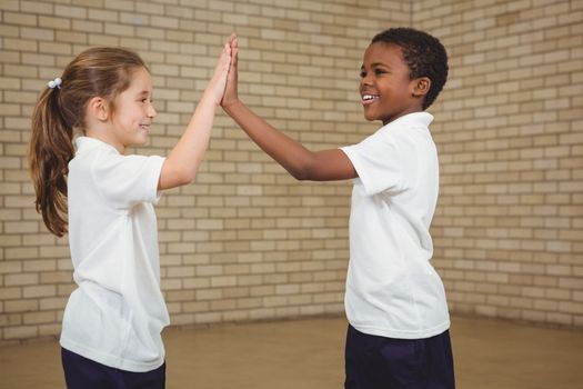 Happy pupils giving each other a high five at the elementary school