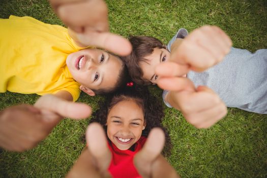 Cute pupils lying on grass smiling on elementary school campus