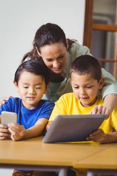 Cute pupils in class using phone and tablet at the elementary school