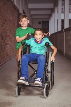 Smiling student in a wheelchair and friend beside him on the elementary school grounds