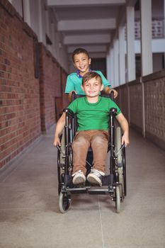 Smiling student in a wheelchair and friend pushing on the elementary school grounds
