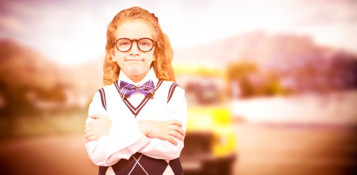 Cute pupil with arms crossed against yellow school bus waiting for pupils