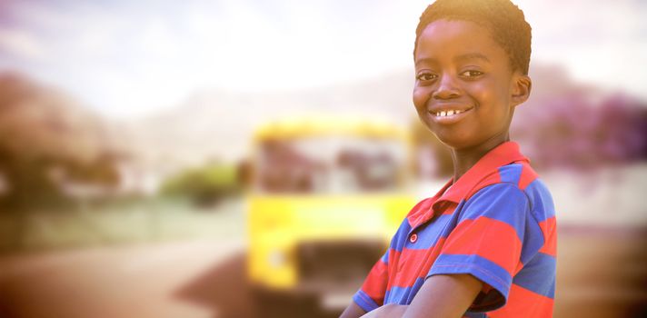 Cute little boy smiling at camera against yellow school bus waiting for pupils
