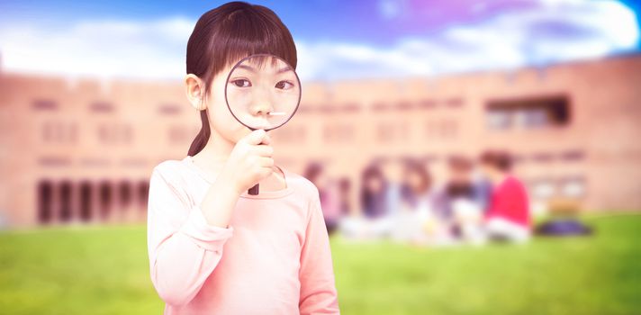 Pupil looking through magnifying glass against students using laptop in lawn against college building