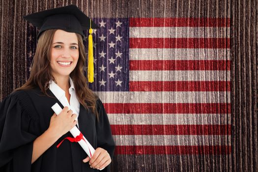 A smiling woman with a degree in hand as she looks at the camera against composite image of usa national flag