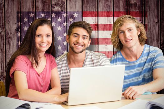 College students using laptop in library against composite image of usa national flag