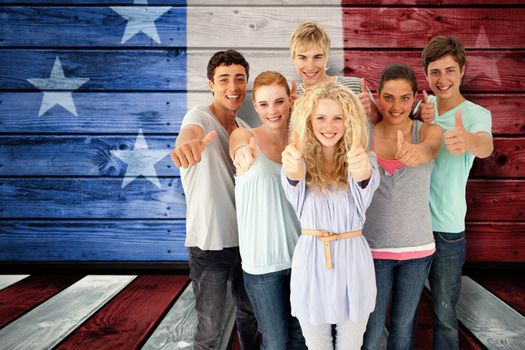 Group of teenagers standing in front of the camera with thumbs up against composite image of usa national flag