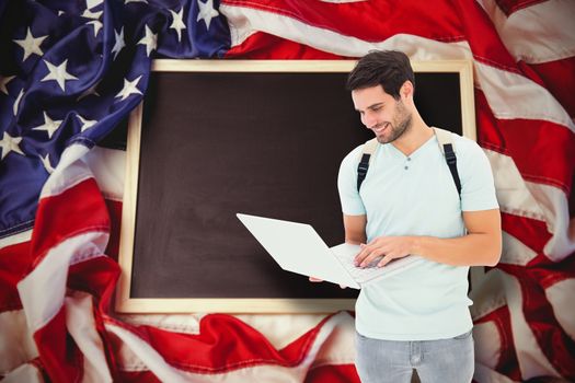 Student using laptop against american flag on chalkboard