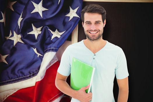 Student holding notepad against american flag on chalkboard