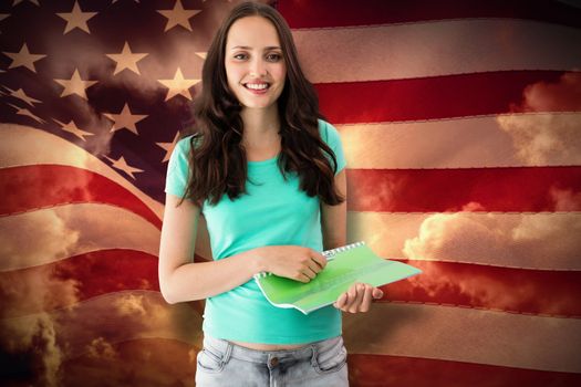 Portrait of smiling young woman with file against composite image of digitally generated united states national flag