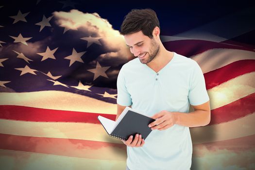Student reading book against composite image of digitally generated american flag rippling