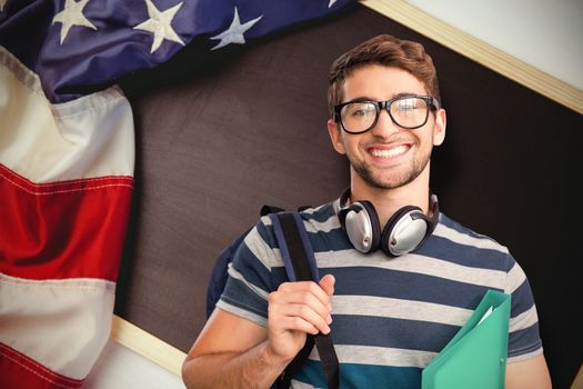 Happy student against american flag on chalkboard