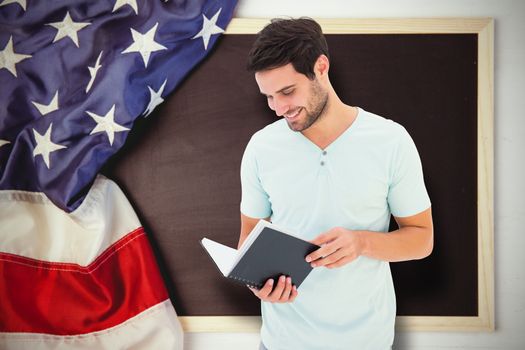 Student reading book against american flag on chalkboard