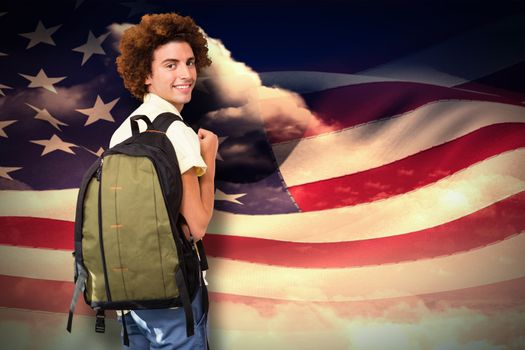 Casual young man in office corridor against composite image of digitally generated american flag rippling