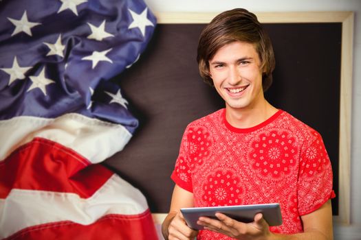 Smiling student with tablet against american flag on chalkboard