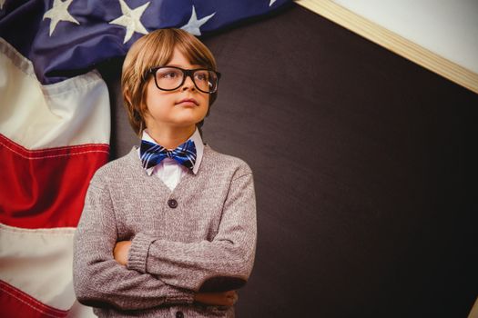 Cute pupil dressed up as teacher against american flag on chalkboard