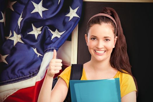 Student with thumbs up against american flag on chalkboard