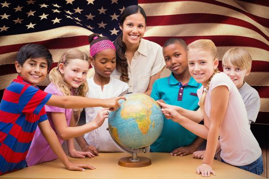 Cute pupils and teacher looking at globe in library against composite image of digitally generated united states national flag