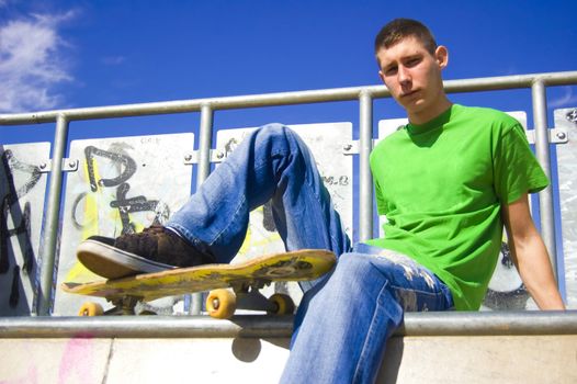 Skateboarder conceptual image. Skateboarder sits in skatepark.