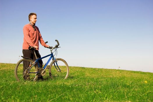 Travel conceptual image. Biker on green field, looks at the landscape.