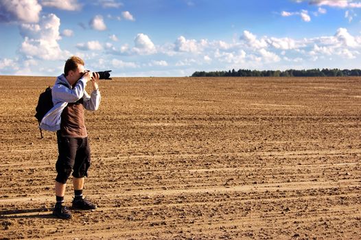 Professional photographer taking pictures on plowed field.