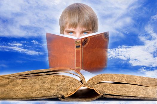Education conceptual image. Open book on background with learning boy aganist blue sky.