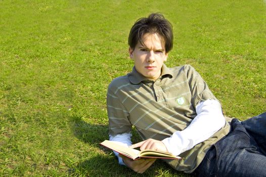 Education conceptual image. Teenager reading a book outdoors.