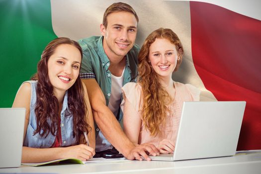 Fashion students using laptop against digitally generated italian national flag