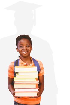 Cute little boy carrying books in library against silhouette of graduate