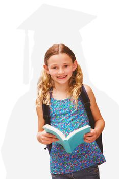 Cute little girl reading book in library against silhouette of graduate