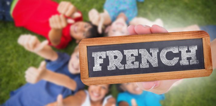 The word french and hand showing chalkboard against happy friends playing in the park